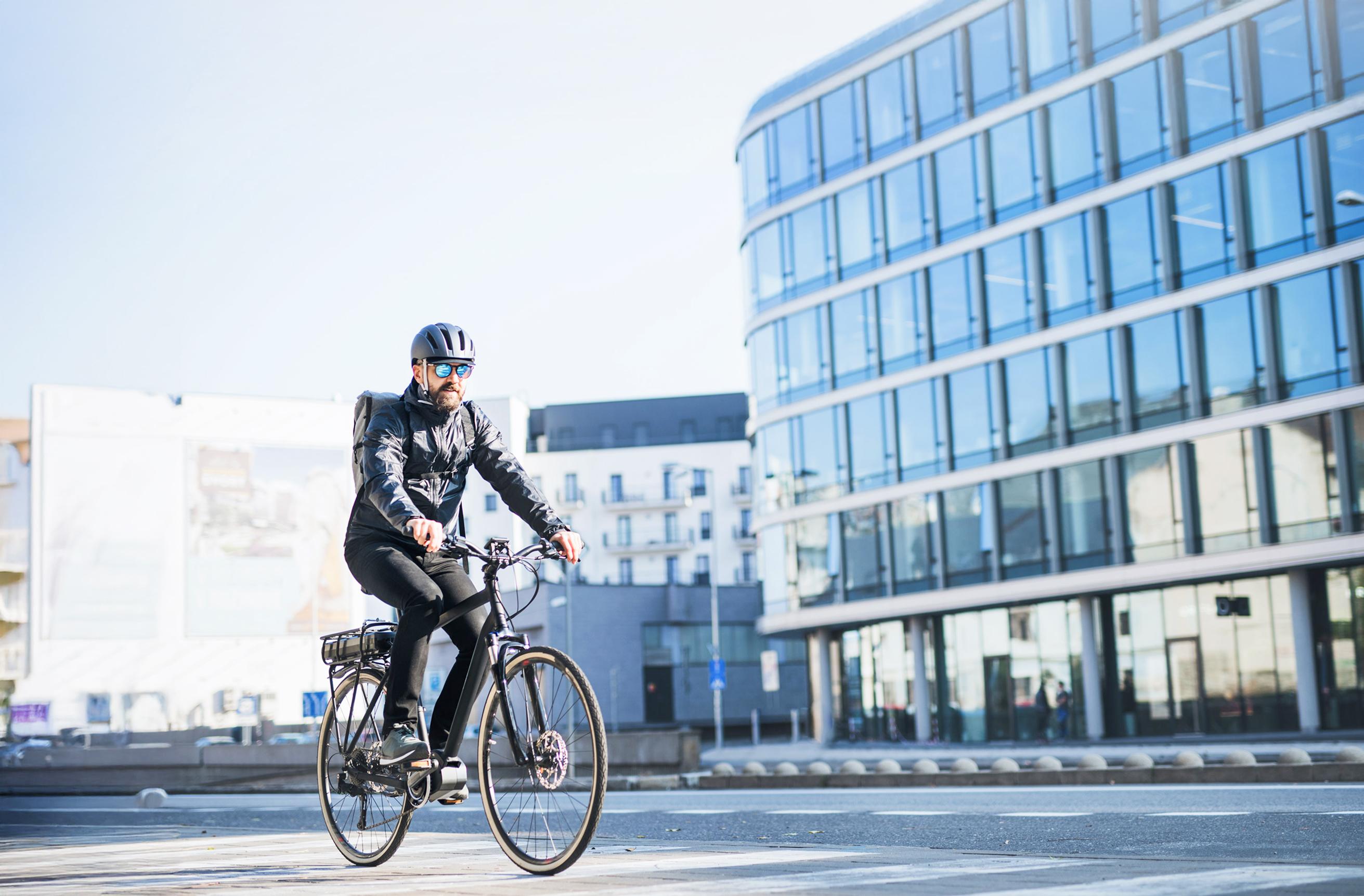 Mann auf einem E-Bike fährt durch die Stadt und hat einen Helm auf.